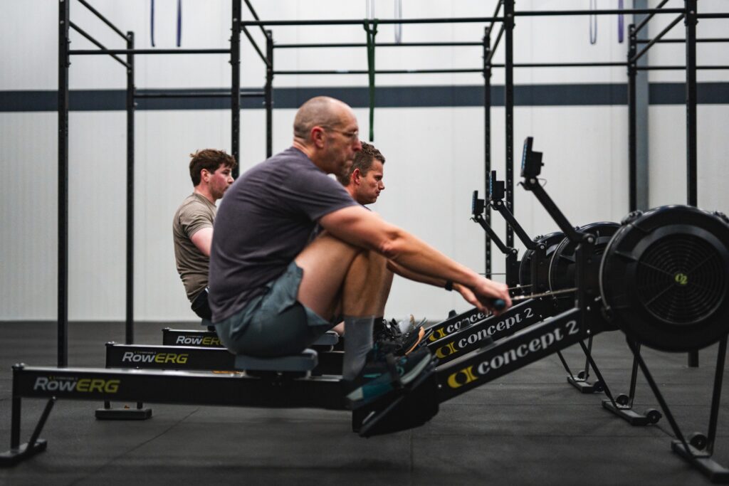 Sporters op de roeitoestellen tijdens een HYROX-training